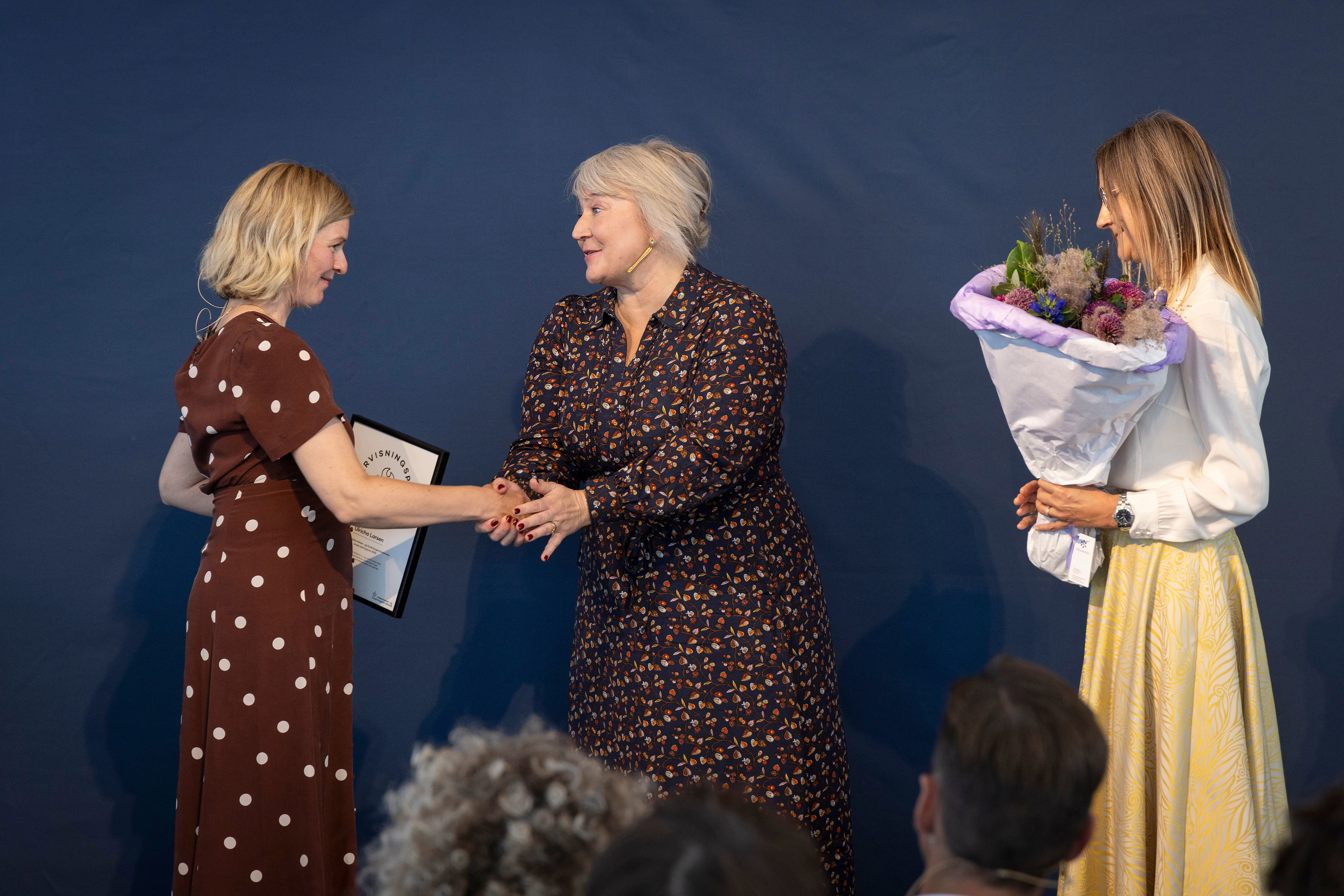 Ulricha Larsen, vinder af Undervisningsprisen 2025, får overrakt diplom og blomster af uddannelses- og forskningsminister Christina Egelund og departementschef Hanne Meldgaard.